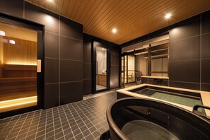 Un spa moderne doté d’un plafond en bois, d’un grand jacuzzi et d’un espace sauna.