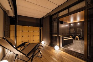 Un espace spa moderne doté d’un plancher en bois, d’une table de massage et d’une cabine de douche en verre.