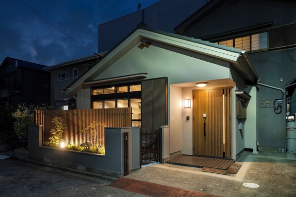 Un immeuble résidentiel moderne doté d’un toit en pente, d’une porte d’entrée en bois et d’un petit espace porche.