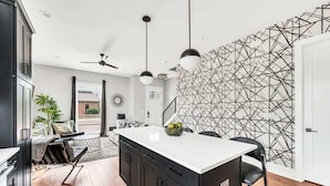 A modern kitchen with black cabinets, a white countertop, and a geometric wall design. - Luxury Rooftop Townhome w/ Skyline Views /Broadway (Nashville)