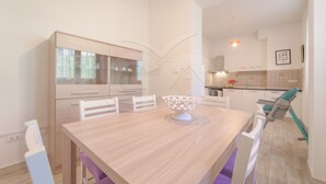 Una cocina moderna con armarios blancos, una mesa de comedor con sillas y una isla de cocina visible.