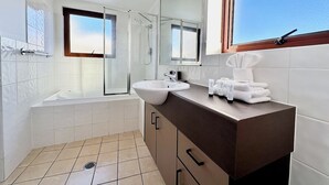 Ein modernes Badezimmer mit einer Badewanne, einem Waschbecken und einem großen Spiegel.