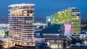 Ein modernes Hotel mit mehreren Etagen, einem geschwungenen Design und einer Dachterrasse.
