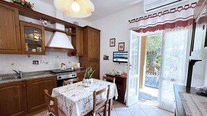 A kitchen with wooden cabinets, a stove, and a dining table with chairs. - Maggy's Home - Maggy's Home (2) (Capoliveri)