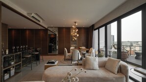 Una sala de estar moderna con sofá, comedor y ventanas amplias que ofrecen vistas a la ciudad.