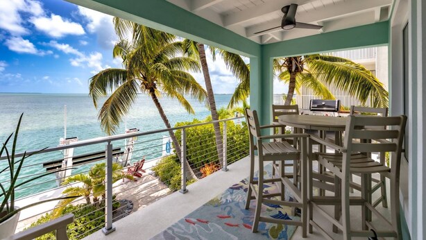 A balcony with a view of the ocean, palm trees, and a grill. - Sunset Serenity – Open Water Paradise | Dockage, Sunset Views, Dog Friendly & Minutes to Key West (Summerland Key)