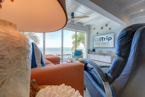 A modern room with a view of the ocean, a ceiling fan, a sign for 'iTrip Key West', and a leather chair.