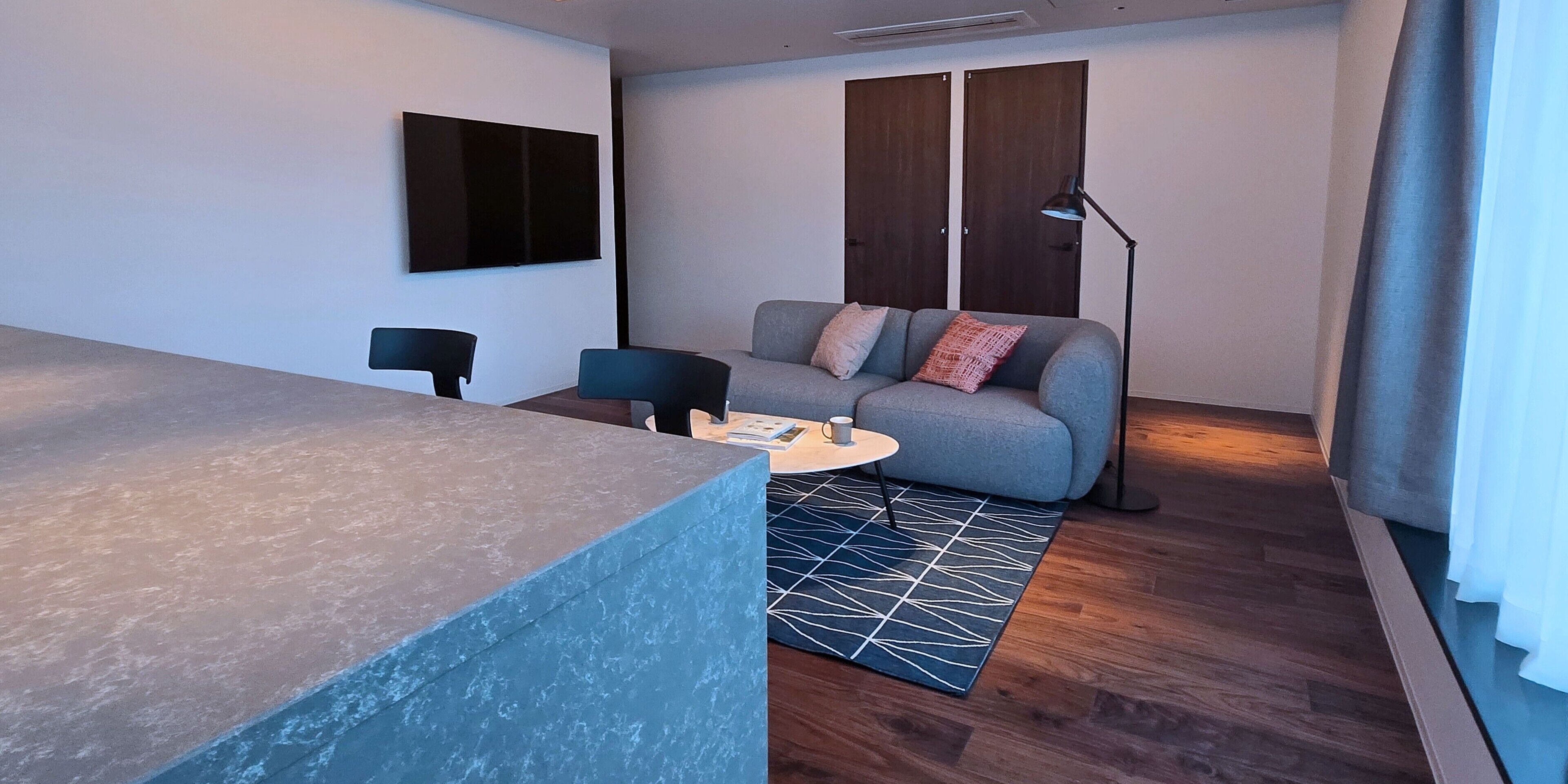 A modern living room with a sofa, coffee table, and a flat-screen TV mounted on the wall.