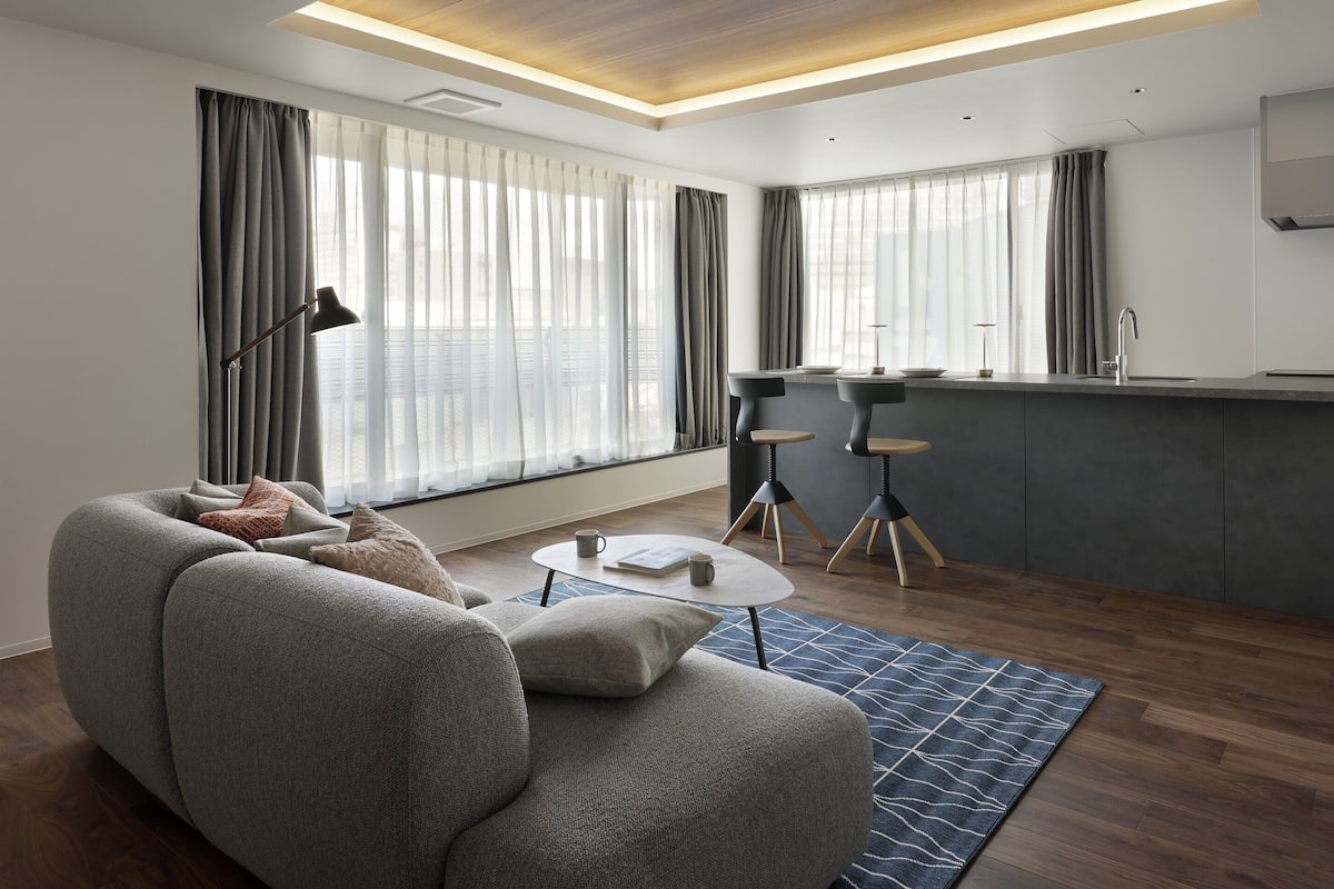 A modern living room with a sofa, coffee table, and a kitchen area with a bar counter.