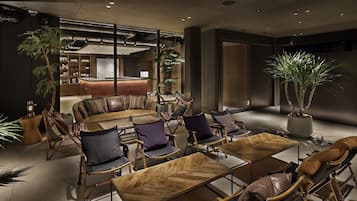 A modern lounge area with a leather sofa, wooden coffee tables, and comfortable chairs.