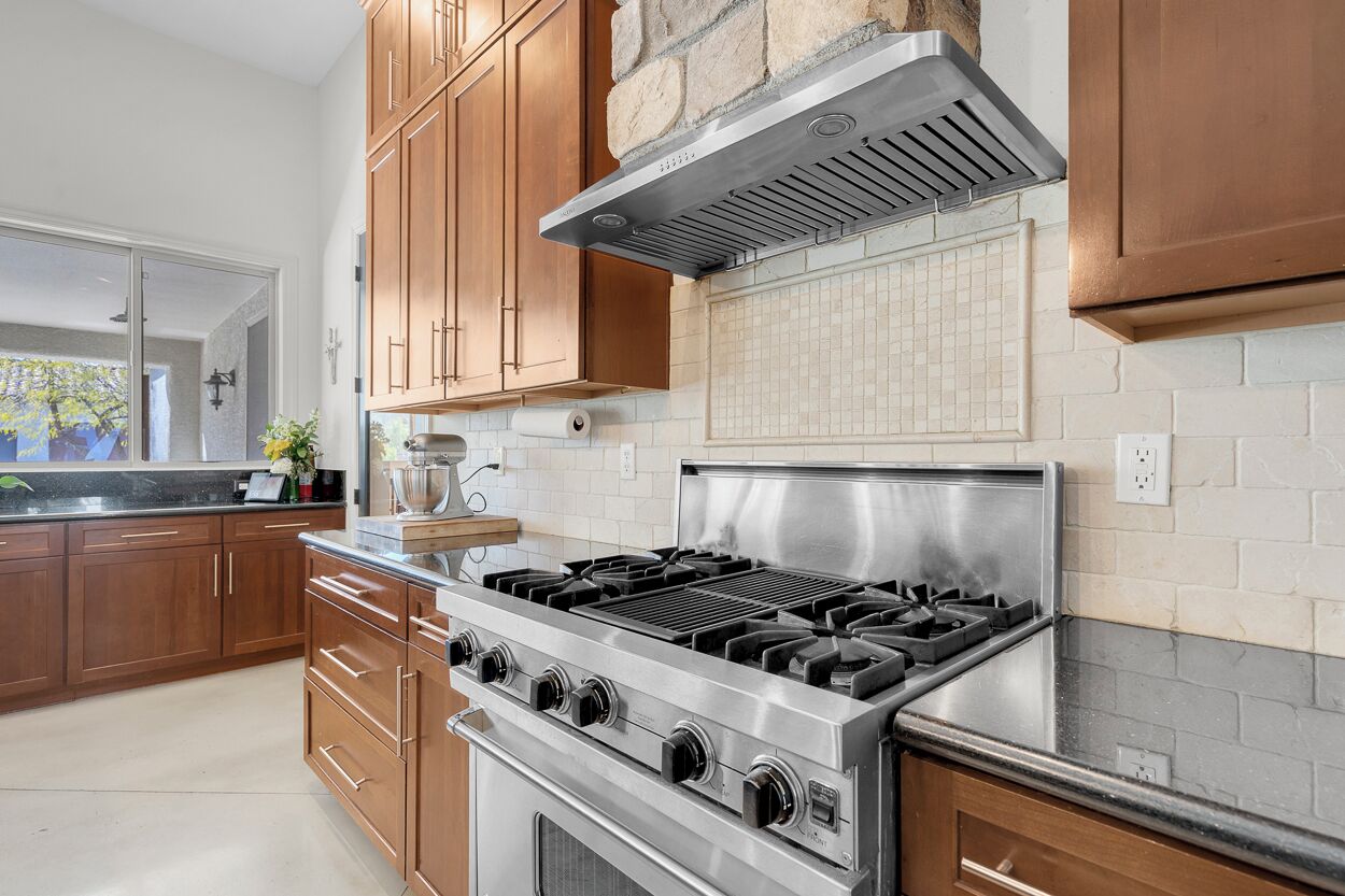 Una cocina moderna con armarios de madera, una estufa de acero inoxidable y una pared decorativa de piedra.