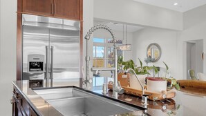 A modern kitchen with stainless steel appliances, a central island, and a pendant light.