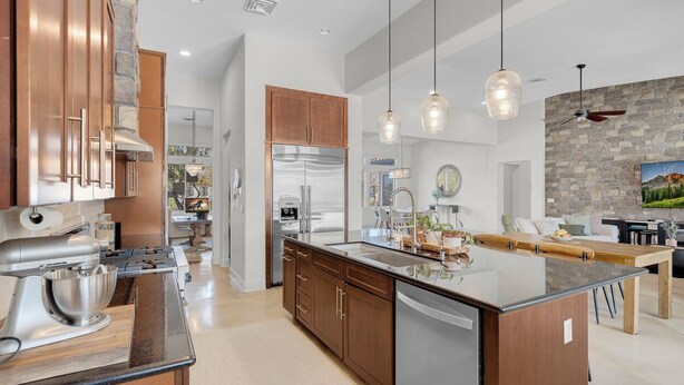 A modern kitchen with stainless steel appliances, wooden cabinets, and pendant lighting.