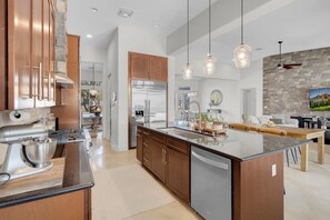 A modern kitchen with stainless steel appliances, wooden cabinets, and pendant lighting.