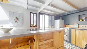 Cozinha moderna com armários de madeira, uma ilha grande, máquina de lavar embutida e uma janela ampla que oferece iluminação natural.