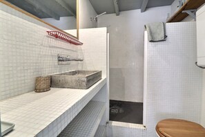 Um banheiro com uma pia retangular, chuveiro e vaso sanitário.