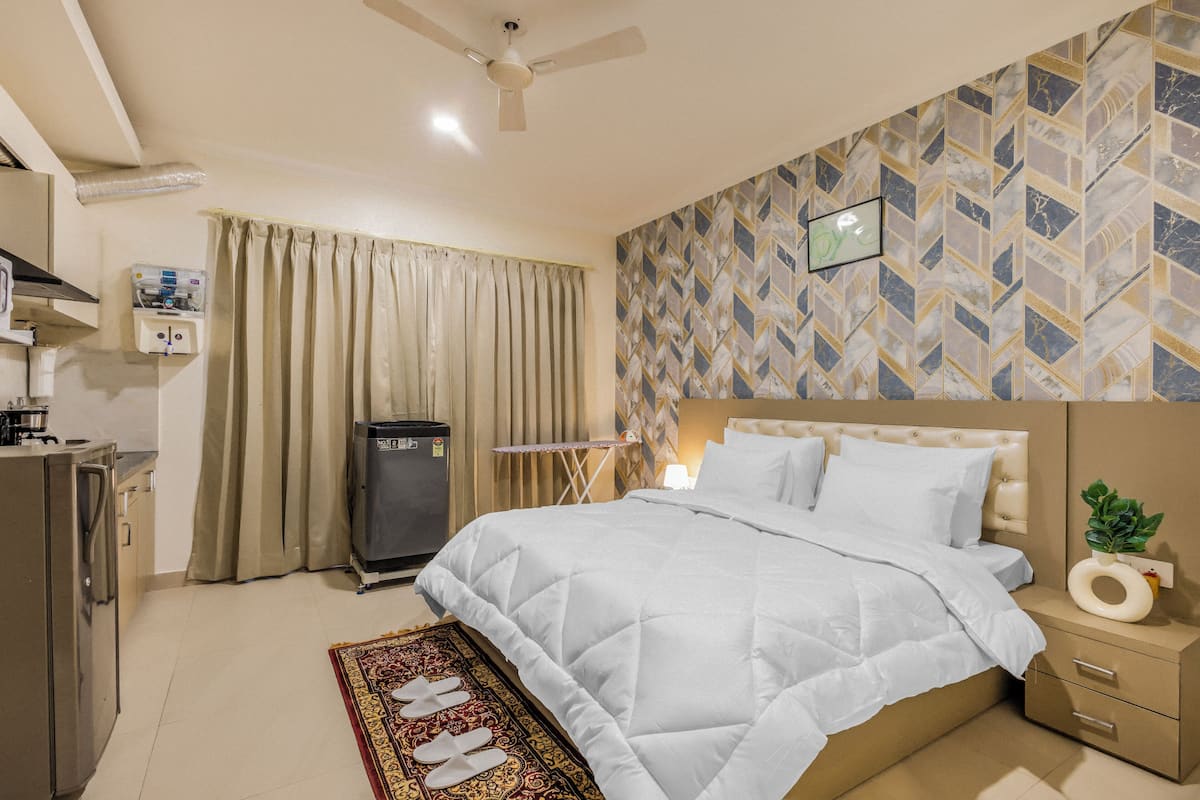Een hotelkamer met een bed, nachtkastje en een klein bureau met stoel.