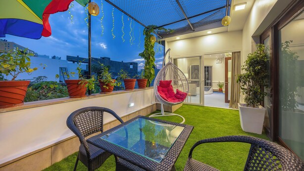 Eine Dachterrasse mit Glastisch, Korbstühlen, einer Hängematte und Topfpflanzen.