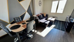A modern living room with a dining table, sofa, and a kitchen area. - One-Bedroom Apartment – Saint-Éloi, Poitiers (Poitiers)