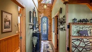 Un couloir en bois, agrémenté d’une porte décorative, d’un tapis et d’éléments décoratifs fixés au mur.
