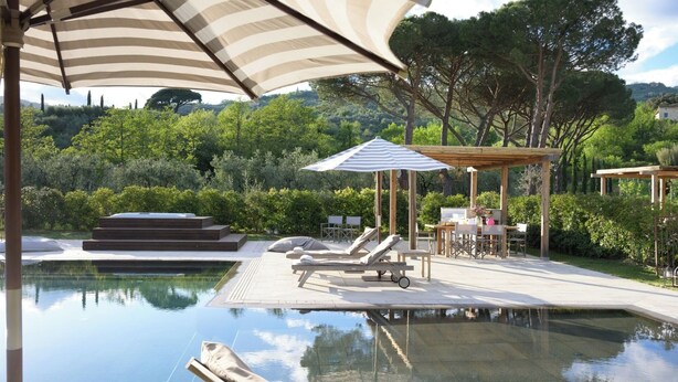 A pool area with lounge chairs, a hot tub, and a pergola with a striped umbrella. - Villa La Pace near Lucca (Province of Pistoia)