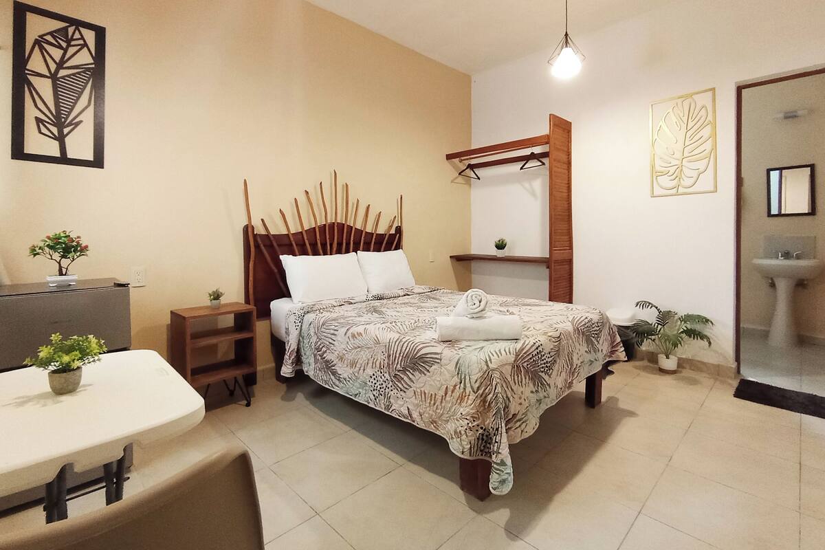 A bedroom with a bed, bedside table, and a small desk with a chair.