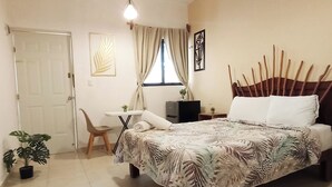 A bedroom with a bed, a desk, a chair, a ceiling fan, and a window with curtains. - Hotel Posada Clarita (Isla Holbox)