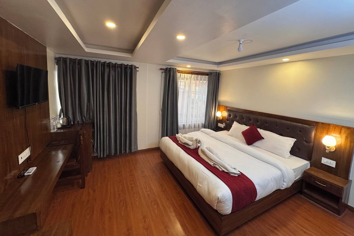 A hotel room with a large bed, wooden furniture, a flat-screen TV, and a ceiling fan.
