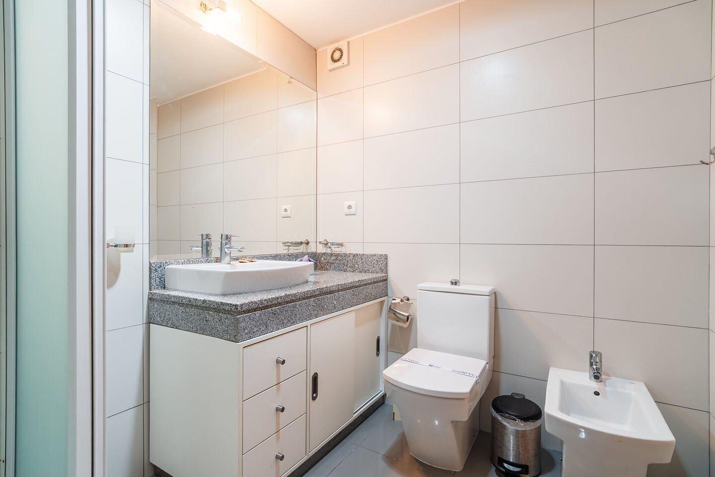 Et badeværelse med toilet, bidet og håndvask.