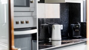 A modern kitchen with a coffee maker, a coffee machine, and a kettle on the countertop. - GuestReady - Homely stay in Funchal (Funchal)