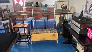 Una habitación con piso azul, muebles de madera, cafetera, microondas, refrigerador y una estantería.