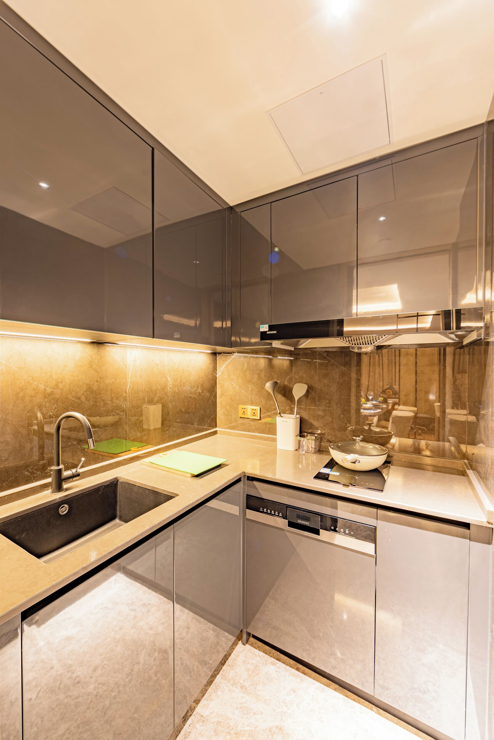 A modern kitchen with a dishwasher, stainless steel cabinets, and a marble countertop.