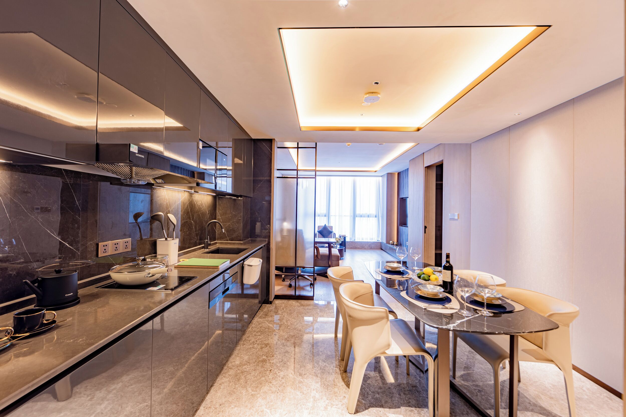 A modern kitchen with a dining area, featuring a large island, built-in appliances, and a view into the living room.