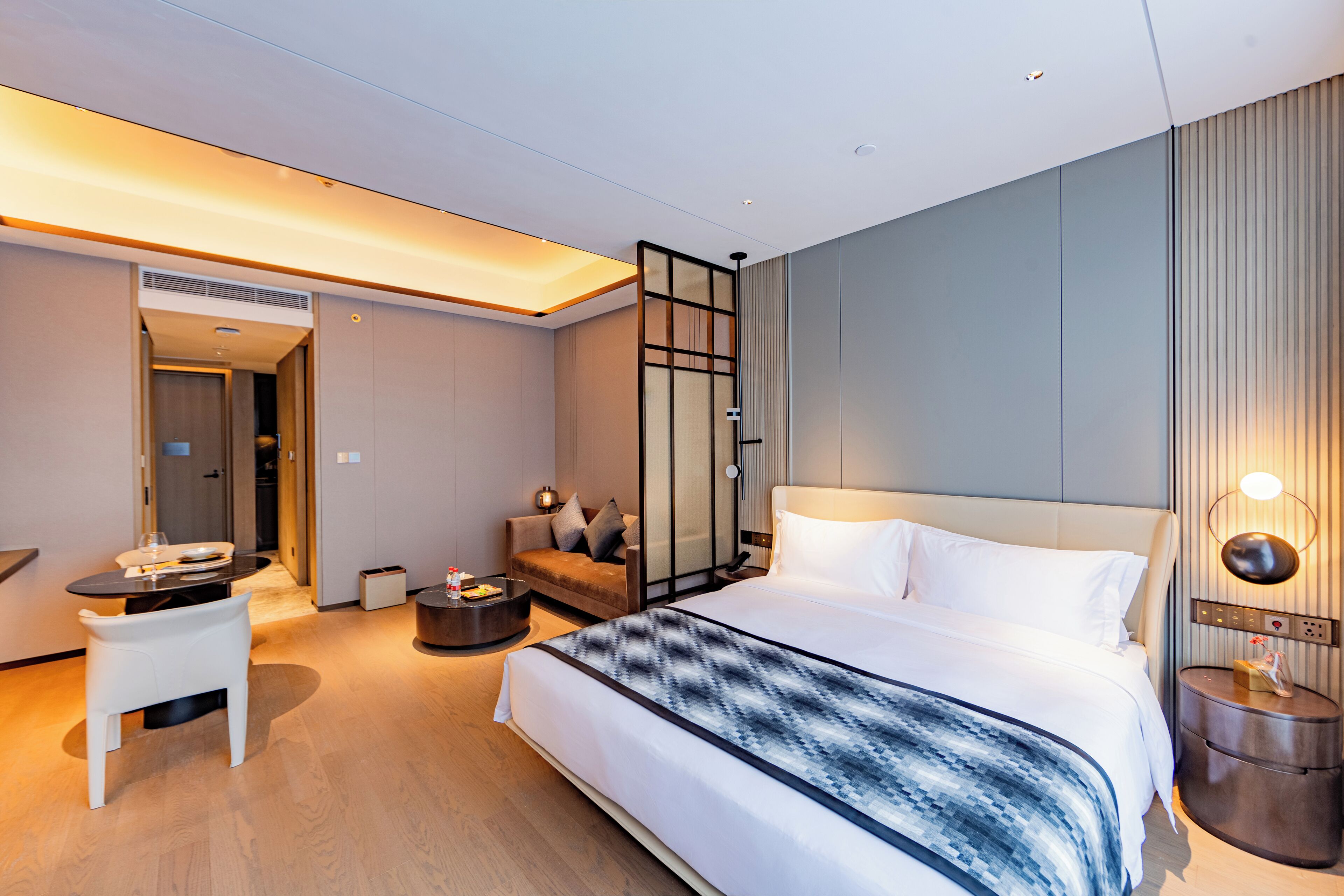 Une chambre d’hôtel moderne dotée d’un grand lit, d’un bureau, d’un canapé et d’une salle de bain séparée.