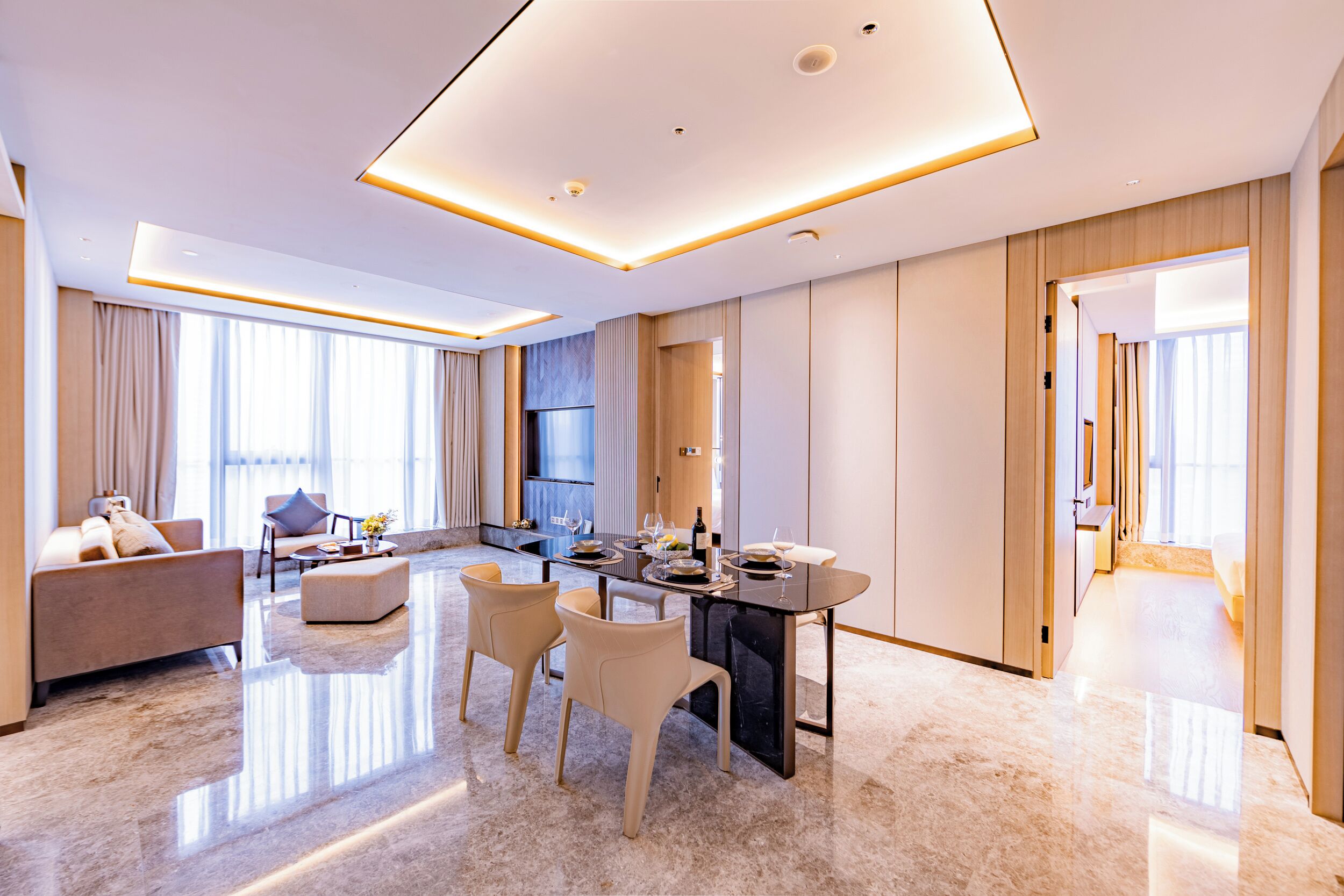 A modern hotel room with a dining area, a sofa, and a kitchen.