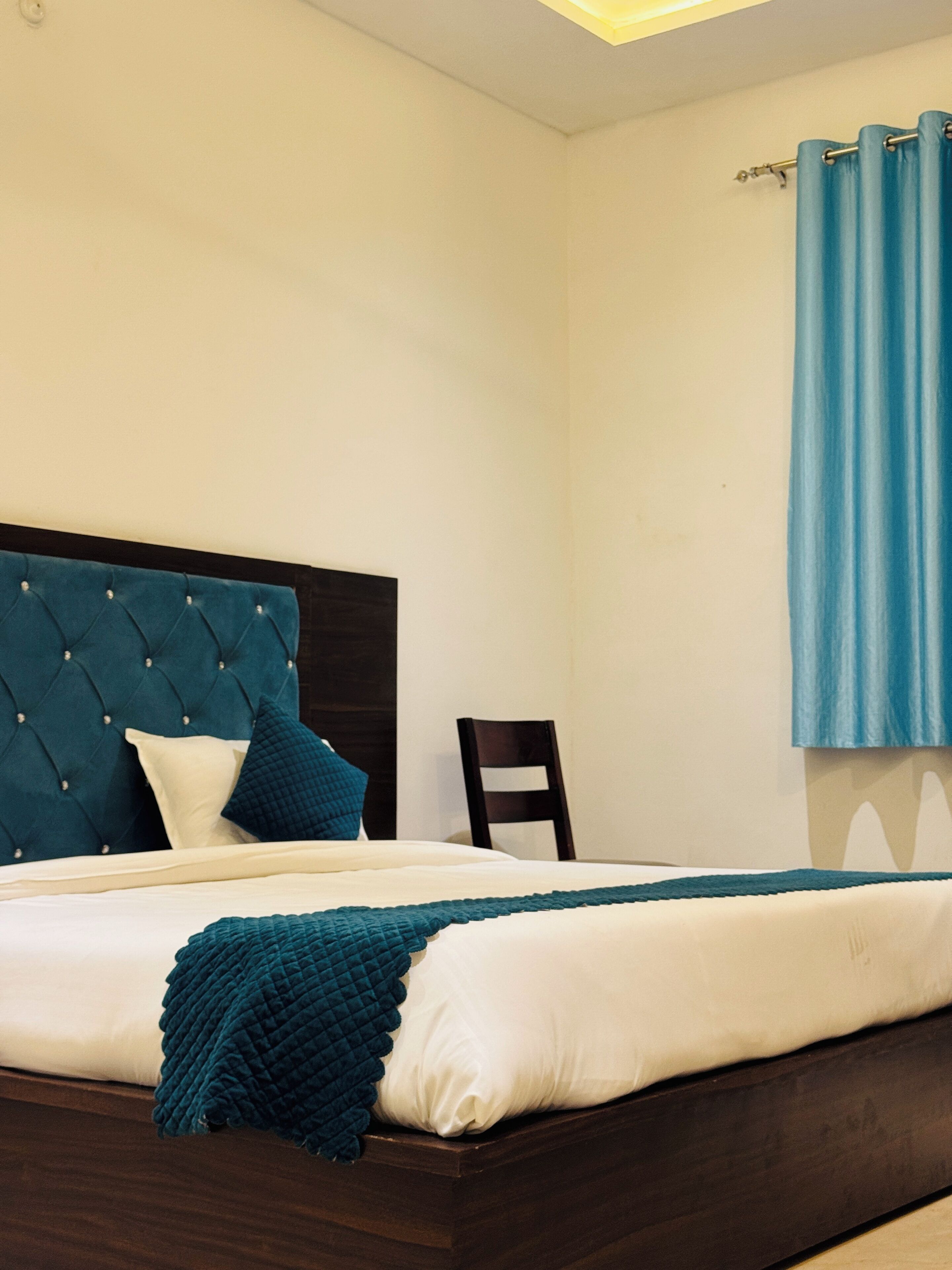 Una cama bien hecha con un cabecero verde azulado, almohadas blancas y una manta verde azulado.