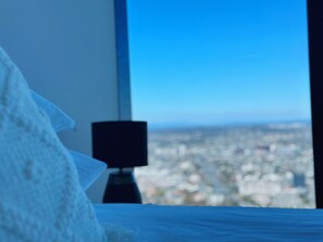 Enjoy a city view from the comfort of this room, featuring a bed and a nightstand with a lamp.