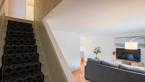 Eine Treppe mit einem geometrischen Muster, ein graues Sofa, ein Flachbildfernseher und ein Gemälde an der Wand.