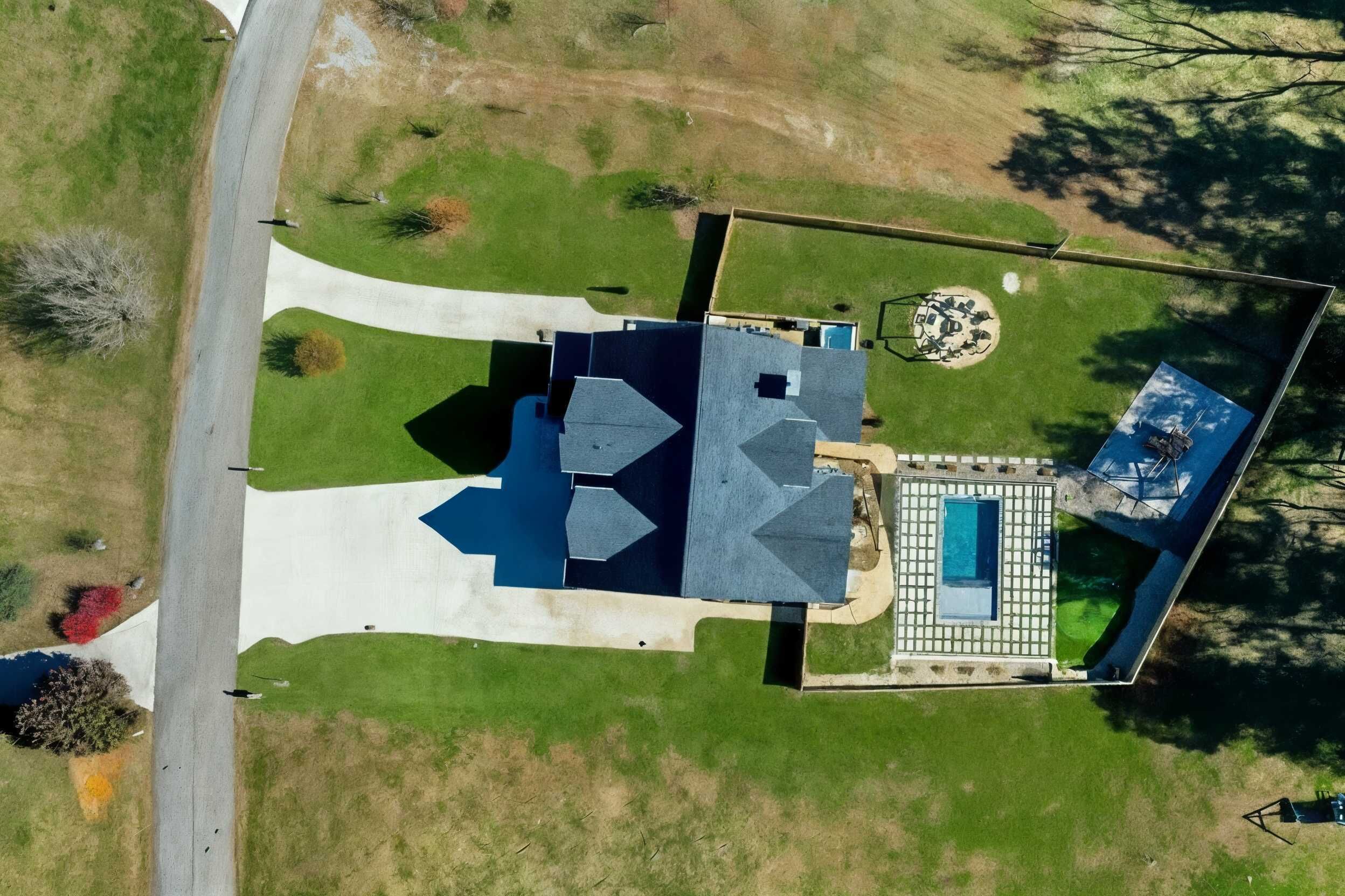 Vue aérienne d’une propriété dotée d’une piscine, d’un espace patio et d’une grande pelouse.