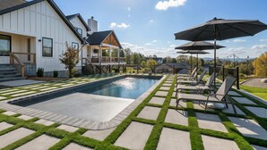 Une maison moderne dotée d’une piscine, de chaises longues et de parasols pour l’extérieur.
