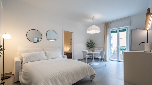 A modern hotel room with a large bed, a dining area, and a balcony with a view. - Appartamento con balcone vicino a Castelvecchio (Verona)