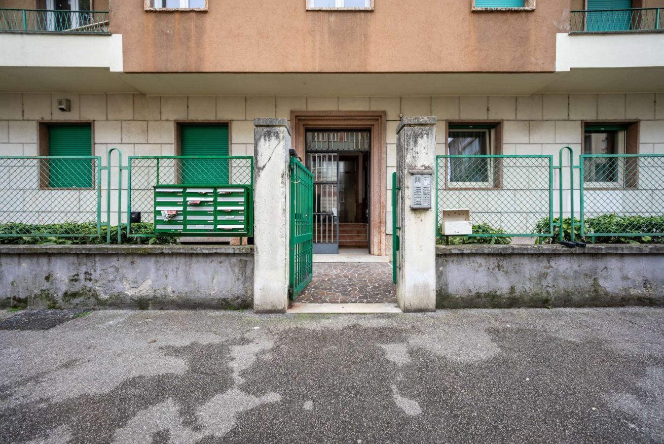 Un edificio con una entrada central, puertas verdes y un pequeño camino que lleva a la puerta.