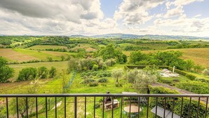 A balcony with a view of rolling green hills and vineyards.