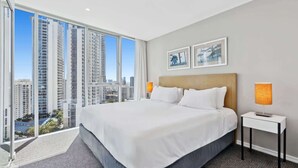 A hotel room with a large bed, two bedside lamps, a nightstand, and a city view through floor-to-ceiling windows. - Modern 2-Bed with Pool Access in Surfers Paradise (Surfers Paradise)