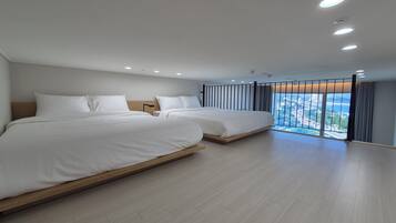 Una habitación de hotel moderna con dos camas, un ventanal con vistas e iluminación empotrada en el techo.