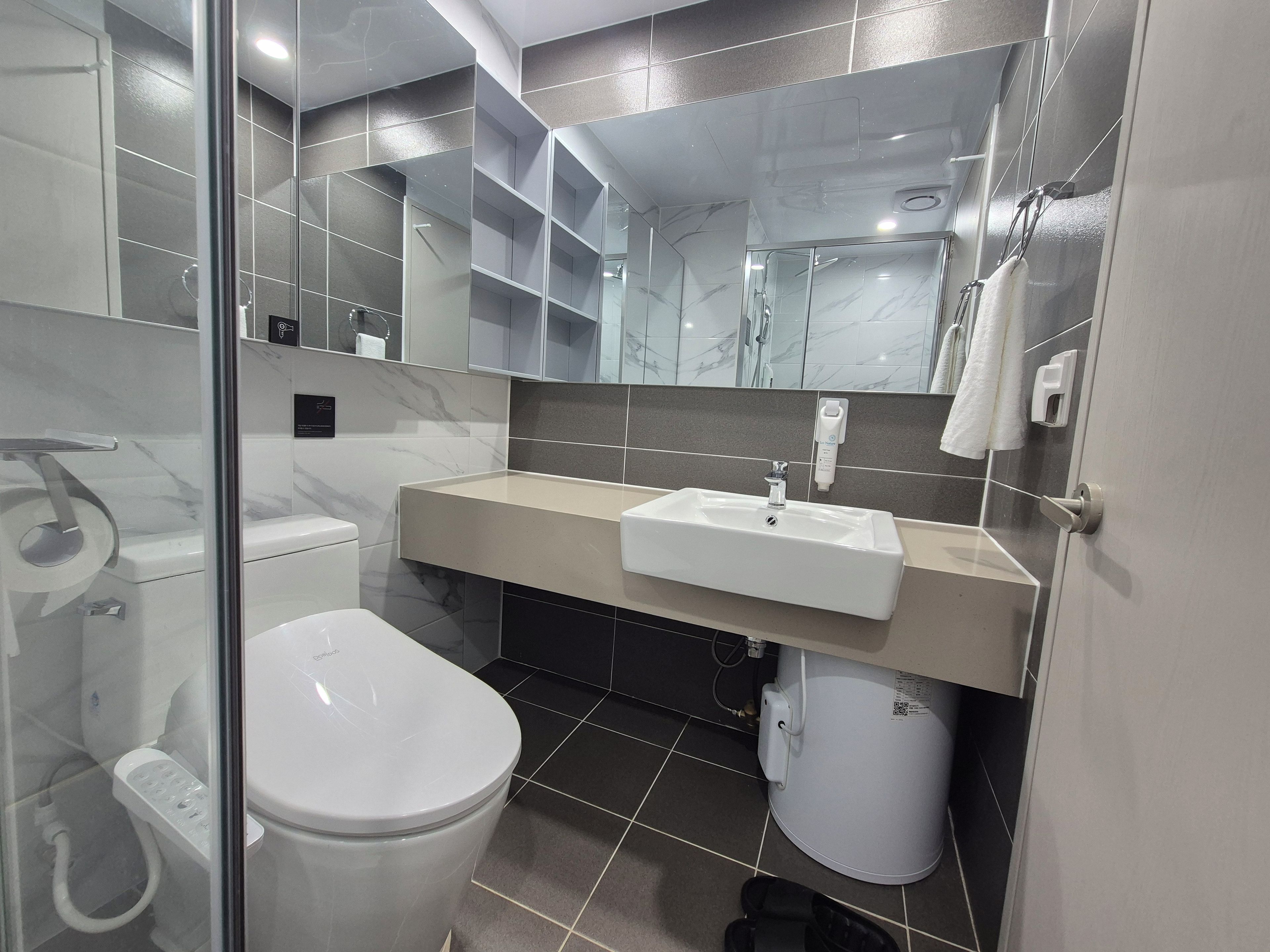 Un baño moderno con inodoro, lavamanos y cabina de ducha de vidrio.