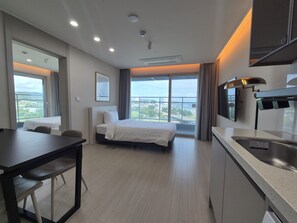 A hotel room with a bed, a desk, a chair, a kitchenette, and large windows offering a city view. - Diamer Hotel Yangyang By Stayneo (Yangyang)