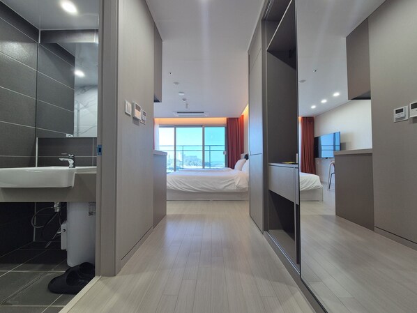 Une chambre d’hôtel avec une salle de bain, un lit, une télévision et une fenêtre avec des rideaux.