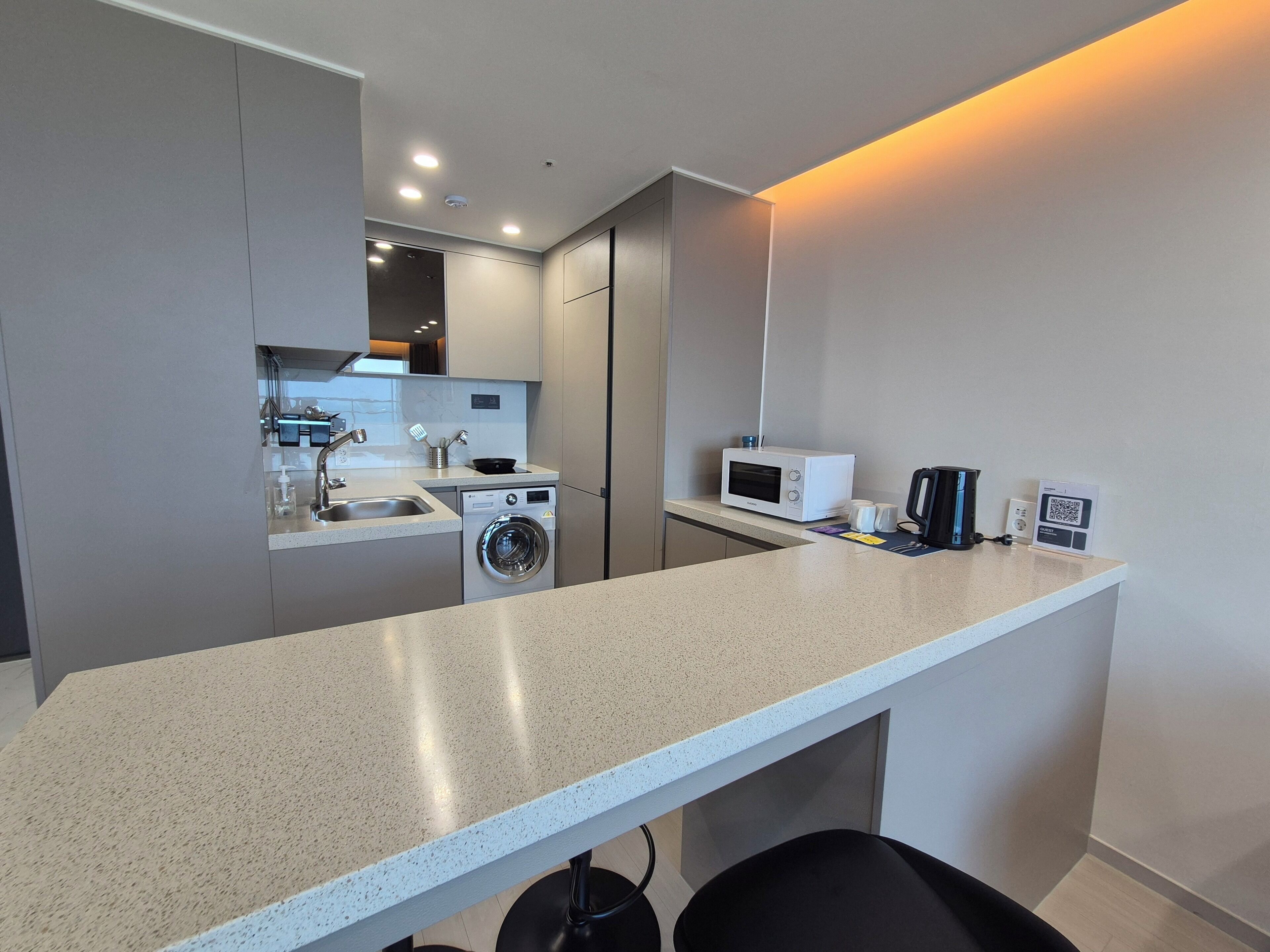 A compact kitchen with a washing machine, microwave, and coffee maker.