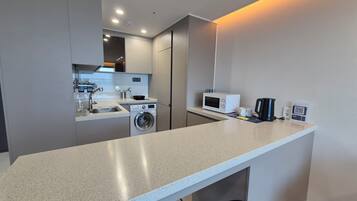 A compact kitchen with a washing machine, microwave, and coffee maker.